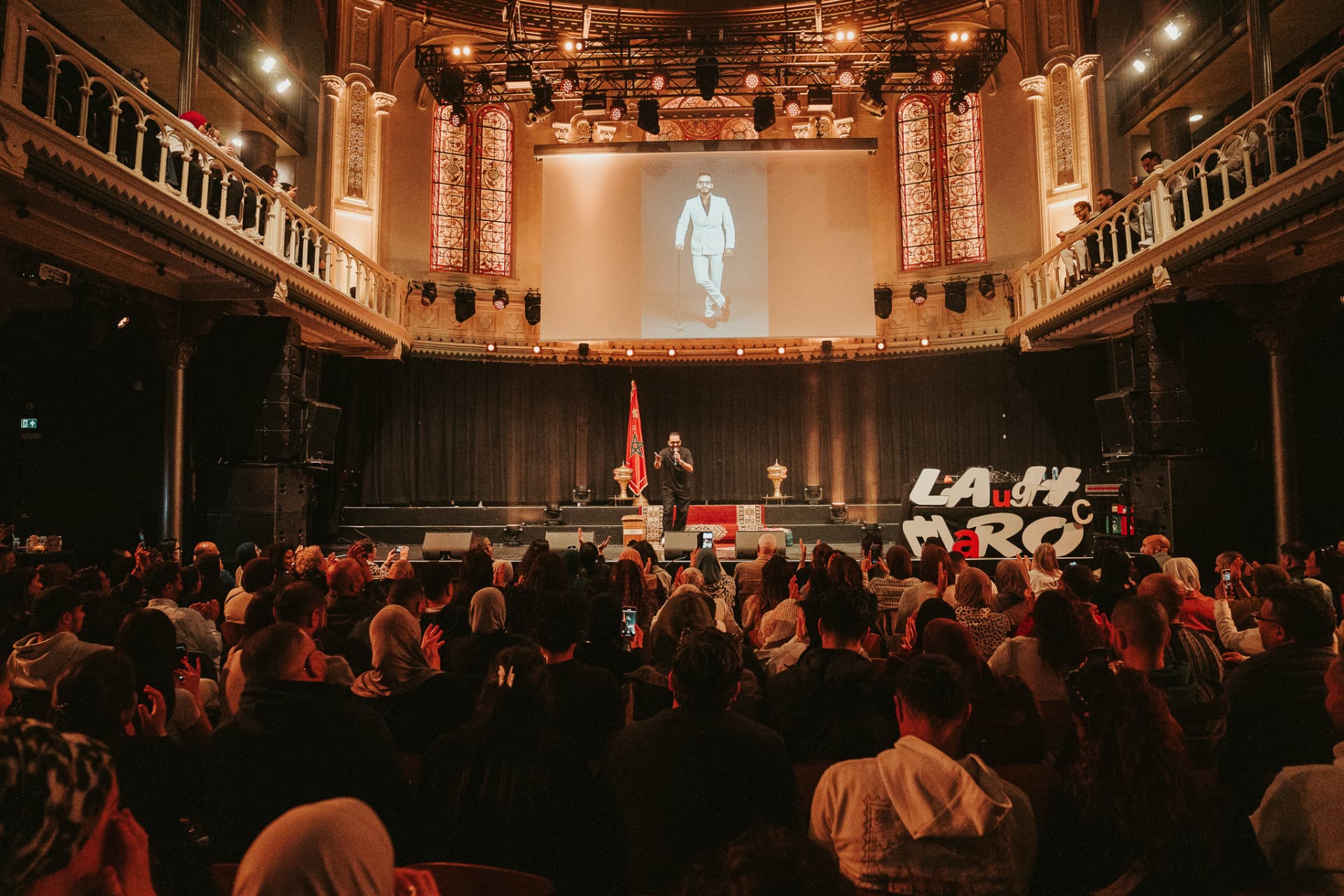 De cast van Laugh Maroc poseert met de Marokkaanse vlag op het podium